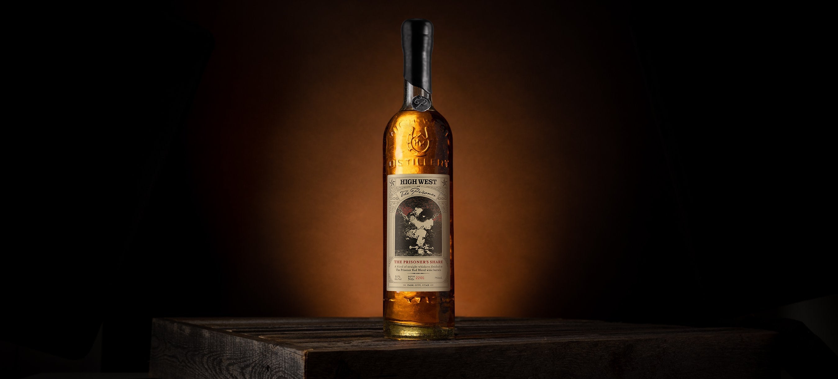 bottle of the prisoners share whiskey on a wooden crate on a brown background